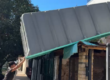 Operario sosteniendo el borde de un casco de pileta de fibra de 7x3 elevado sobre el techo de una casa, visto desde la vereda