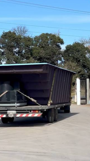 Camion con el casco de una pileta de fibra atado a la carroceria, llegando al ingreso de un barrio cerrado